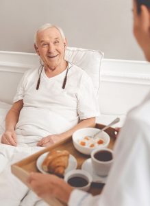 Patient wearing BeHear ACCESS headset receives meal from orderly.